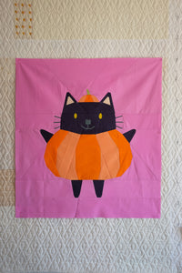 Patchwork quilt with a cat-shaped pumpkin design on a pink background The Weekend quilter Halloween Catwalk series Jackie Cat mini Quilt pattern