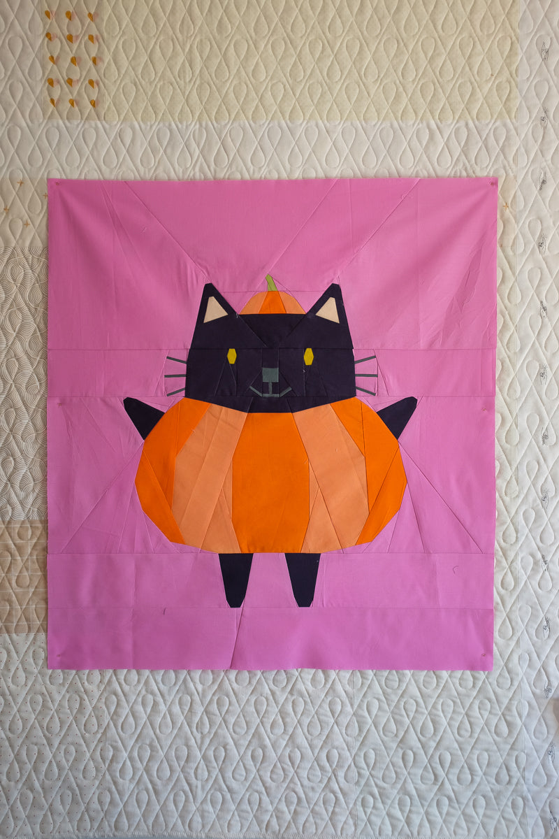 Patchwork quilt with a cat-shaped pumpkin design on a pink background The Weekend quilter Halloween Catwalk series Jackie Cat mini Quilt pattern