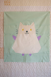 Children's dress with cat design on a light green background. The Weekend Quilter Mistie cat mini quilt pattern from halloween catwalk series