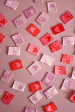 Load image into Gallery viewer, A vibrant flat lay of The Weekend Quilter&#39;s Hugs and Kisses woven labels in shades of pink, red, and pastel. The design includes &quot;XOXO&quot; motifs and reversible heart labels with light and dark sides, perfect for enhancing quilts, bags, and handmade sewing projects with a colorful, personalized touch.