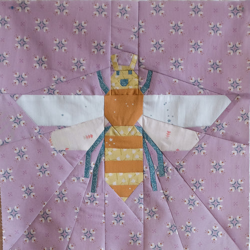foundation paper pieced FPP Quilt block with a bee design on a purple floral background. Pollen Gatherer foundation paper pieced (FPP) quilt block designed by The Weekend Quilter.  fabrics all from the GeoBloom Fabric collection for AGF 