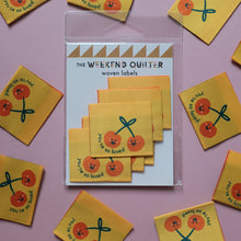 Load image into Gallery viewer, Pack of woven labels with cherry design and 'The Weekend Quilter' branding on a pink background.